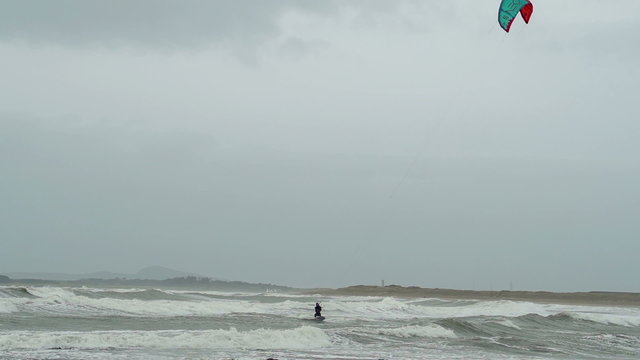 Kite surfers are surfing on large storm waves in North Wales as a stormy winter hits.