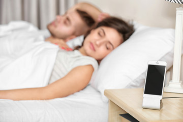 Obraz na płótnie Canvas Happy couple waking up with mobile alarm clock