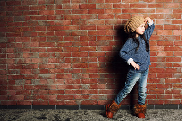 Portrait of little fashion kid girl on bricks wall background