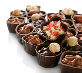 Delicious chocolate candies on white background, close up