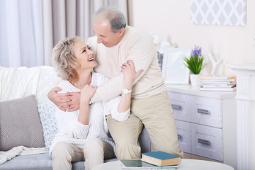 Mature couple sitting and embracing together on a sofa  at home