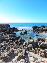 Fototapeta na wymiar Rocks in the water, cliff coast. Coastline with copy space.