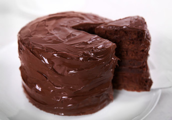 Chocolate cake on plate with a cut piece on unfocused background, closeup