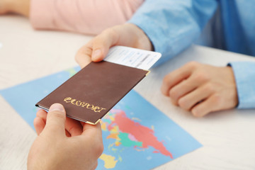 Agent giving passport and ticket to customer in the office of travel company