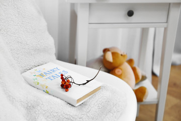 An open book, rowan on the blanket and a teddy-bear in the room