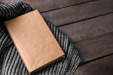 A book and a woolen blanket on wooden background