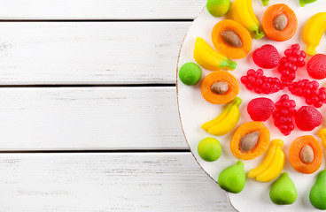 Fruit candies on mat on wooden background