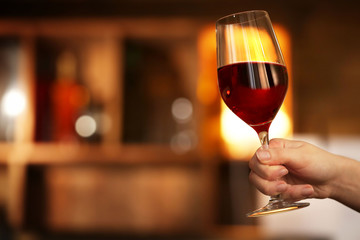 Female hand holding glass of wine in the bar