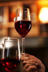 Male hand holding glass of wine in the bar
