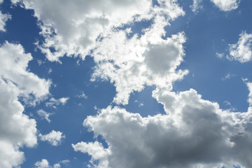 White clouds in ultramarine sunny sky with sun backlight
