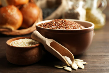 Composition of sesame, flax, pumpkin seeds and buns on wooden table background, closeup