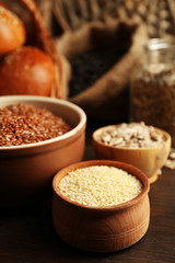 Composition of sesame, flax, sunflower seeds and buns on wooden table background, closeup