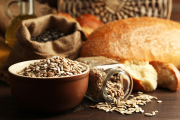 Composition of sunflower seeds and bread on wooden table background, closeup