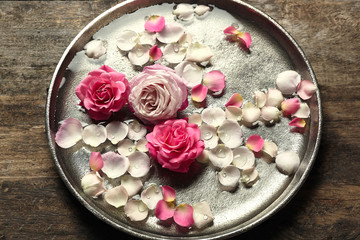 Obraz na płótnie Canvas Pink and white rose petals in silver bowl with water on wooden background