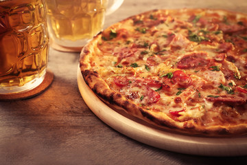 Delicious pizza  and glasses of beer are on wooden table, close up