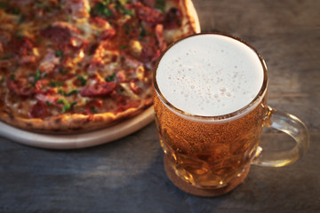 Delicious pizza  and glass of beer are on wooden table