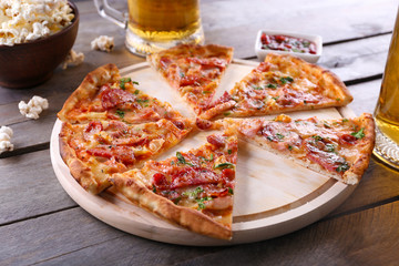 Sliced pizza and glass of beer on wooden table, close up