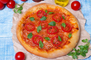 Italian cuisine. Mediterranean cuisine. Pizza Margherita with tomato topped with melted golden cheese, herbs and basil served  on old wooden table