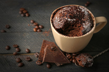 Chocolate fondant cake in cup on wooden background