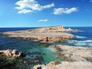 Rocky coastline background and clear blue and turquoise sea with copy space.