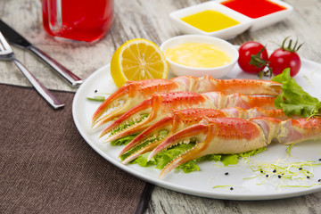 Boiled crab claws with sauce , lemon and cherry tomatoe with tasty drink over wooden background