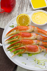 Boiled crab claws with sauce , lemon and cherry tomatoe with tasty drink over wooden background