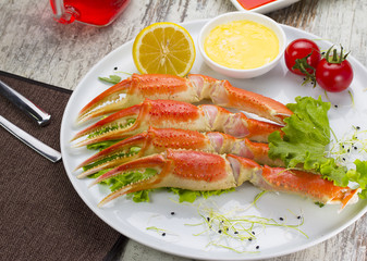 Boiled crab claws with sauce , lemon and cherry tomatoe with tasty drink over wooden background