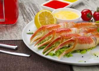 Boiled crab claws with sauce , lemon and cherry tomatoe with tasty drink over wooden background