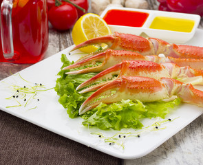 Boiled crab claws with sauce , lemon and cherry tomatoe with tasty drink over wooden background
