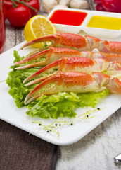 Boiled crab claws with sauce , lemon and cherry tomatoe with tasty drink over wooden background