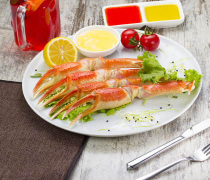 Boiled crab claws with sauce , lemon and cherry tomatoe with tasty drink over wooden background