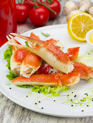 Boiled crab claws with sauce , lemon and cherry tomatoe over wooden background