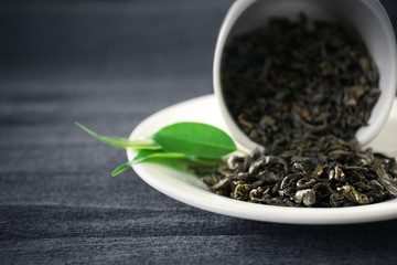 Granulated tea with green leaves in tea-set on grey background