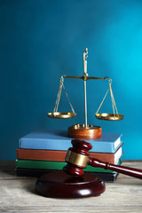 Wooden gavel with justice scales and books on blue background