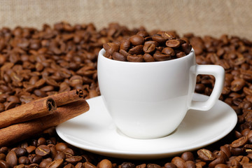 Coffee cup full of coffee beans and cinnamon sticks