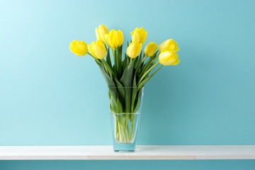 青い背景と棚と花瓶と黄色いチューリップ