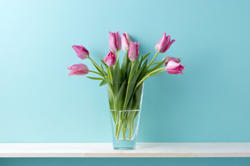 青い背景と棚と花瓶とピンク色のチューリップ