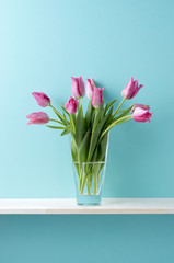 青い背景と棚と花瓶とピンク色のチューリップ