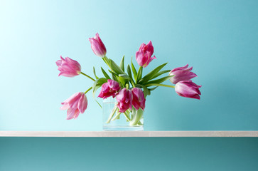 青い背景と棚と花瓶とピンク色のチューリップ