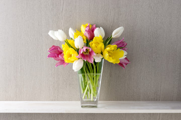 茶色い木目の背景と棚と花瓶と3色のチューリップ