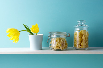 青い背景と棚と黄色いチューリップとショートパスタ