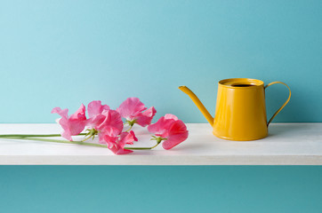 青い背景と棚とスイートピーとジョウロ © kim