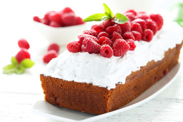 Raspberry cake on plate on white wooden background