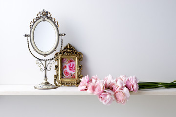 白い背景と棚と写真立てと鏡とラナンキュラス
