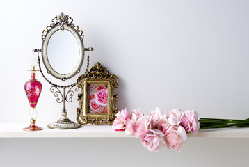 白い背景と棚と写真立てと鏡と香水瓶とラナンキュラス