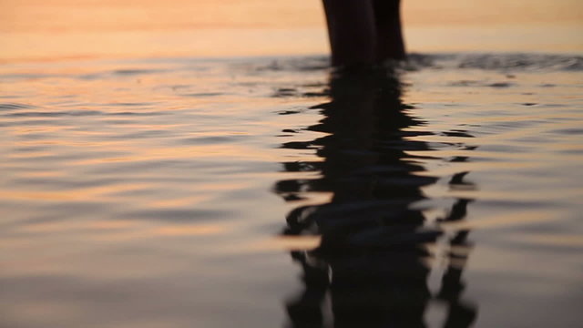Girl reflection in the sea water with cat's-paws and down up motion to she's silhouette walking into the sunrising sea and turn back at the end (720p, 50fps)