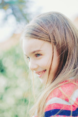 Naklejka premium Spring fairy. Portrait of beautiful little girl with brownish blond hair and blue eyes standing outdoor on natural background.