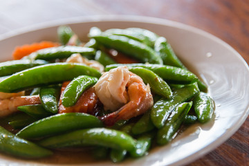 Shrimp stir and fried and green peas on white plate with selective focus