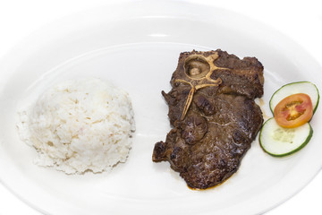 T Bone steak with rice and sauce on a white plate in a restaurant
