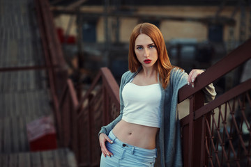 Beautiful redhair young woman in casual closes in urban background. Fashion Photo